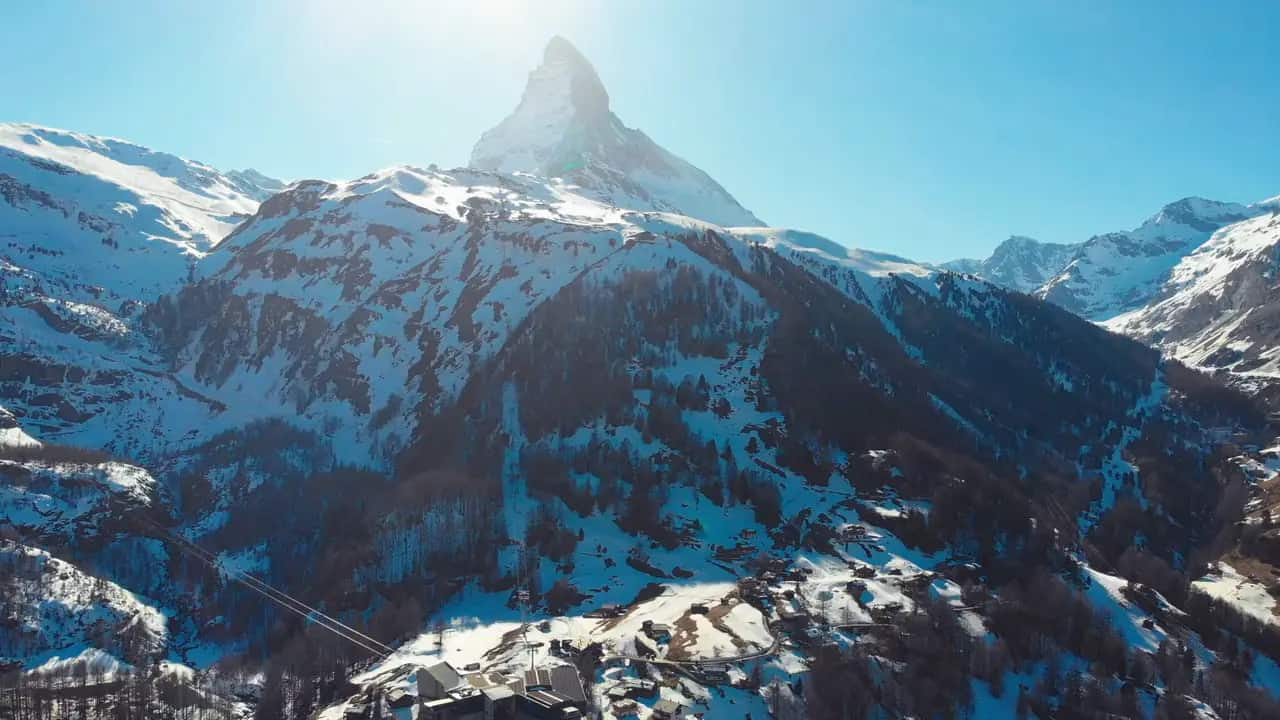The Matterhorn rising above snow-covered Swiss Alps under a deep blue sky